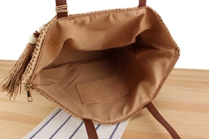 Top view of straw tote bag interior showing the fabric lining and metal zipper closure