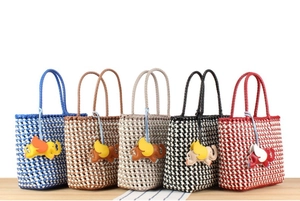 Detailed row of woven plastic tote bags in five colors with cute elephant charms