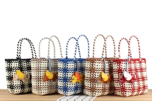 Detail of five colorful hand-woven plastic tote bags with unique small elephant charms
