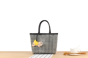 Detailed close-up of checkerboard woven tote bag with a cute elephant pendant