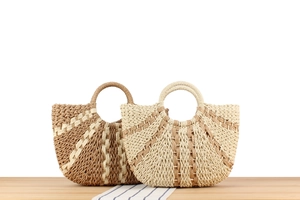 Detail of fan-shaped woven straw handbags with contrast colors and round handle