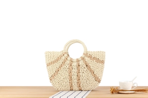 Detail of hand-woven straw tote bag with fan-shaped texture on a wooden table