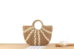 Detailed view of handmade woven straw tote with geometric patterns on a wooden surface