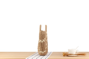 Large woven tote bag in khaki and beige on a wooden table with coffee and dried flowers