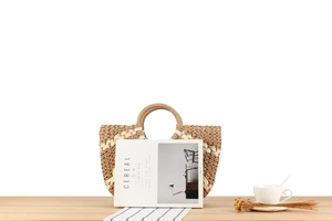 Close-up of woven straw tote bag with dual-tone geometric patterns and circular handles
