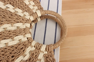 Detailed top view of a large woven straw tote bag with radial pattern on a wooden table