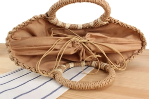 Detail view of woven straw tote bag featuring a secure brown drawstring inner lining