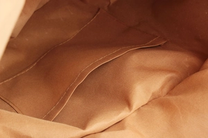 Detail view of the durable brown fabric lining and inner pocket of the large woven tote bag