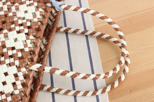 Close-up of brown and white plastic woven handbag showing intricate checkered texture