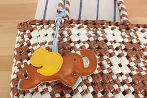 Detail of woven checkerboard handbag with a cute brown leather elephant bag charm