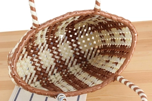 Macro view of woven plastic beach bag featuring a detailed dual-tone twist handle design