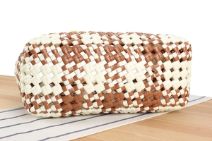 Detail of the woven pattern on a brown and beige plastic tote bag for beach vacations