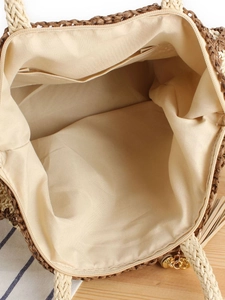 Internal view of straw woven beach bag with fabric lining, zipper pocket and tassel detail