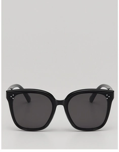 Close-up of black oversized kids' sunglasses with three silver metal dots on the frame