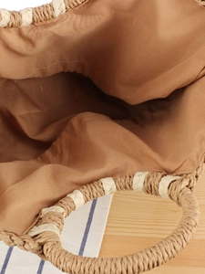 Top view of large straw woven tote with brown fabric lining and white trim handles