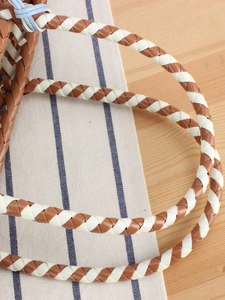Brown and white woven plastic tote bag with light blue accents on wooden background