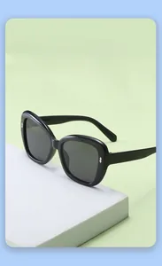 Detail of kids black square sunglasses with silver diamond accent on green background
