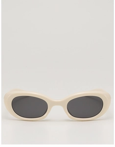 Detail view of oval cream-colored sunglasses with dark grey lenses and smooth frames