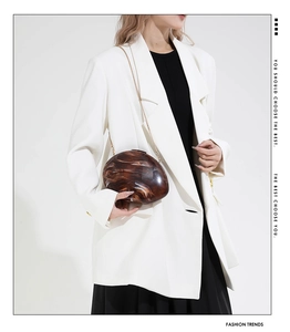 Detail view of amber marble acrylic shell bag with golden chain strap on model