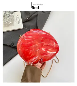 Detail view of red marble acrylic shell evening bag with elegant gold chain strap