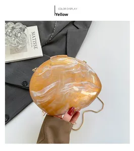 Detail of yellow marble acrylic clutch bag with a sleek gold chain strap on art books