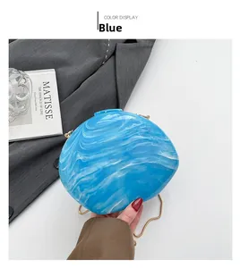 Detail of blue and white marble texture acrylic shell bag with gold chain strap