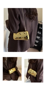 Detail der goldenen Metall-Clutch mit Blasenstruktur und schmaler Kette
