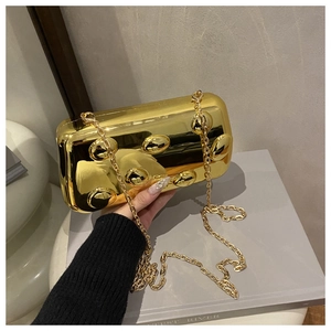 Nahaufnahme der goldenen Metallic-Clutch mit runden Nieten und feiner Kette