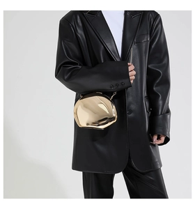 Detail of a golden irregular pebble-shaped clutch bag with polished mirror finish and chain