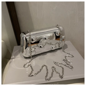 Detailaufnahme einer silbernen Metallic-Clutch mit Blasenstruktur und feiner Kette