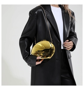 Chic gold mirrored egg-shaped evening clutch bag with metal chain strap on model
