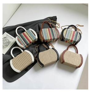 Detail of straw woven bags featuring colorful stripes, rivets and gold chain straps