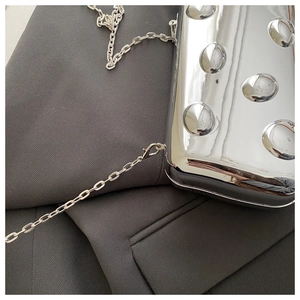Makroaufnahme einer silbernen Spiegel-Handtasche mit 3D-Blasen-Textur und Kette