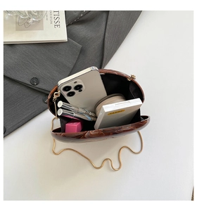 Macro view of acrylic marble evening clutch showing interior space for phone and makeup