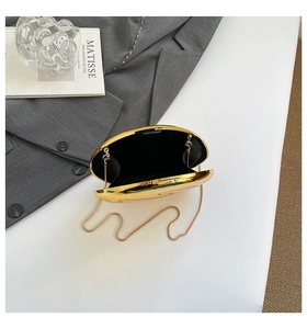 Top view of gold egg-shaped acrylic clutch bag with metal chain and black lining