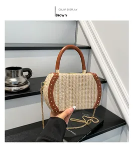Close-up of straw handbag with brown leather trim, silver studs and gold metal chain strap