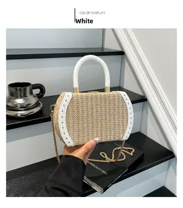 Detail of straw woven handbag with white leather trim and decorative gold metal rivets