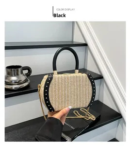 Detail of straw woven handbag featuring black leather trim and gold studs decoration