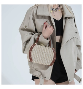 Detail of woven straw handbag featuring gold rivets and brown leather trim handle