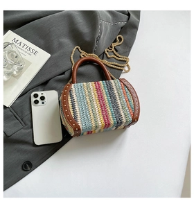Detail of bohemian woven bag with colorful stripes, brown leather trim and gold metal studs