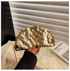 Detail of gold wavy metallic clutch bag with lava texture and elegant chain strap