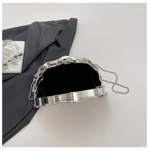 Detail of silver metallic evening bag with wavy edges and elegant chain strap