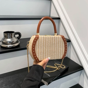 Fashionable straw bucket bag with brown leather trim and metallic rivet details