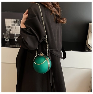 Detailed view of spherical green clutch bag with gold metal handle and chain strap