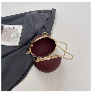 Detailed view of an open burgundy spherical clutch bag with golden chain and metallic frame