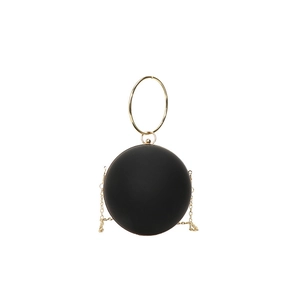 Detail of matte black spherical evening bag with gold ring handle and metal chain