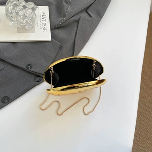 Elegant gold egg-shaped acrylic evening clutch bag with chain strap on a white surface