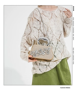 Detail of champagne gold evening bag with rhinestone flower and heart-shaped metal handle