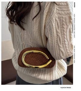 Détail de pochette en daim marron avec strass dorés et poignée anneau métal