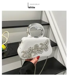 Detailed view of white evening bag with rhinestones and chrome handle on stairs